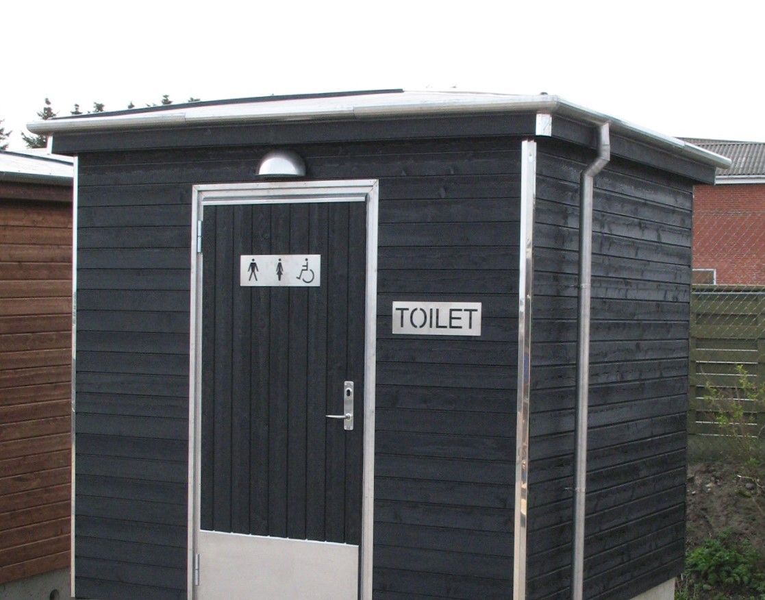 Et lille sort skur med et skilt, hvor der står toilet