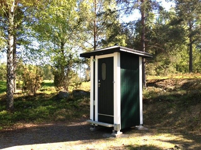 Et lille grønt og hvidt udhus midt i en skov