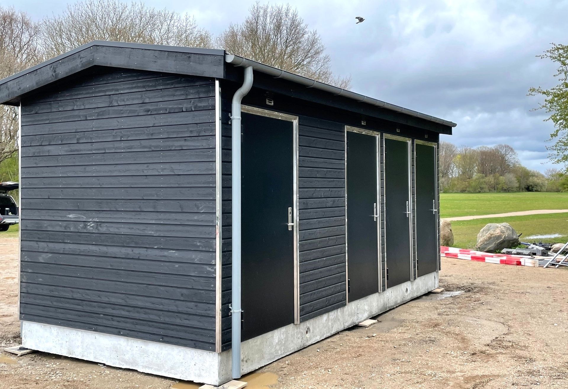 Et lille sort skur sidder midt på en jordmark.