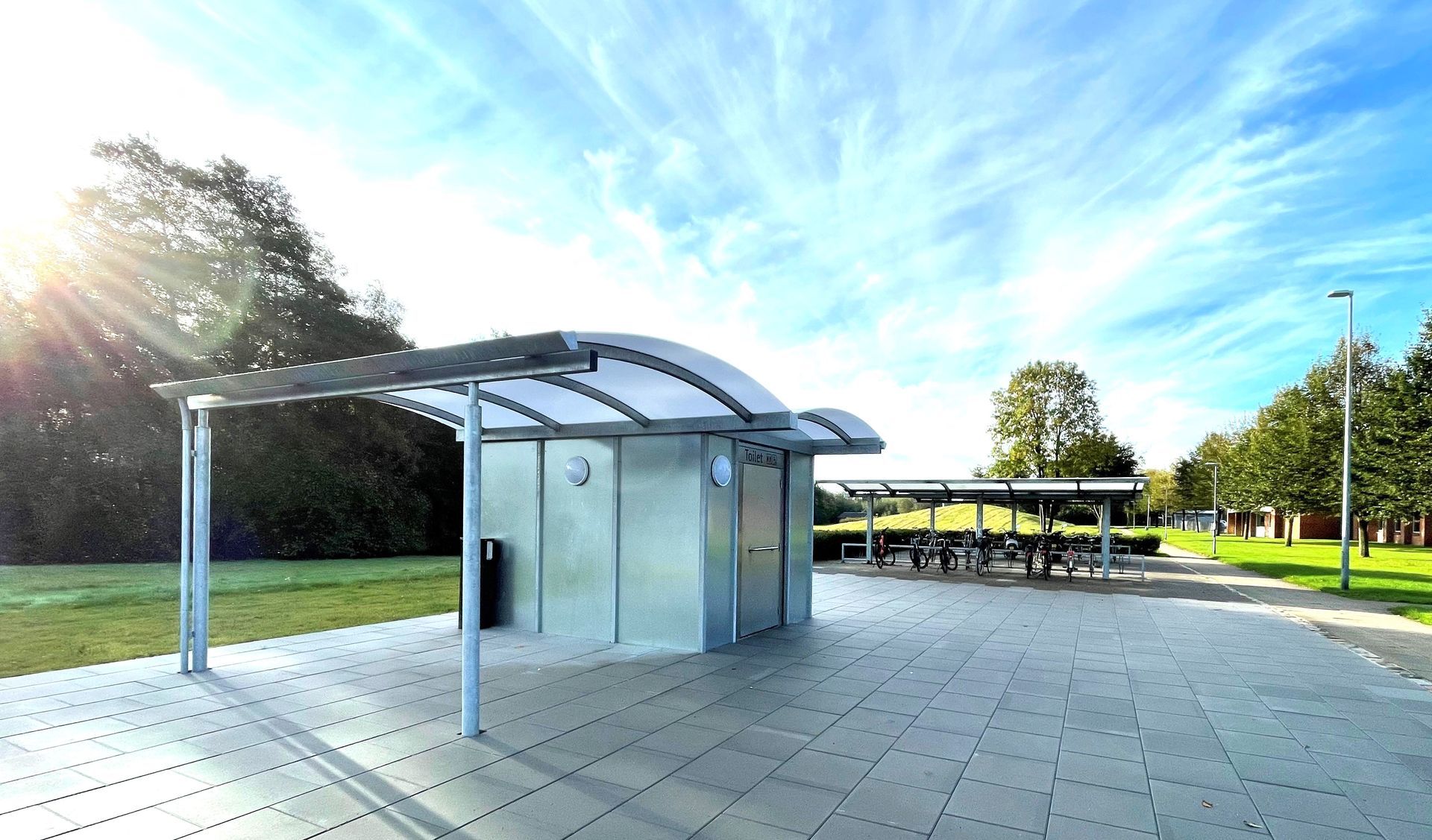 Et shelter i en park med solen skinnende gennem skyerne