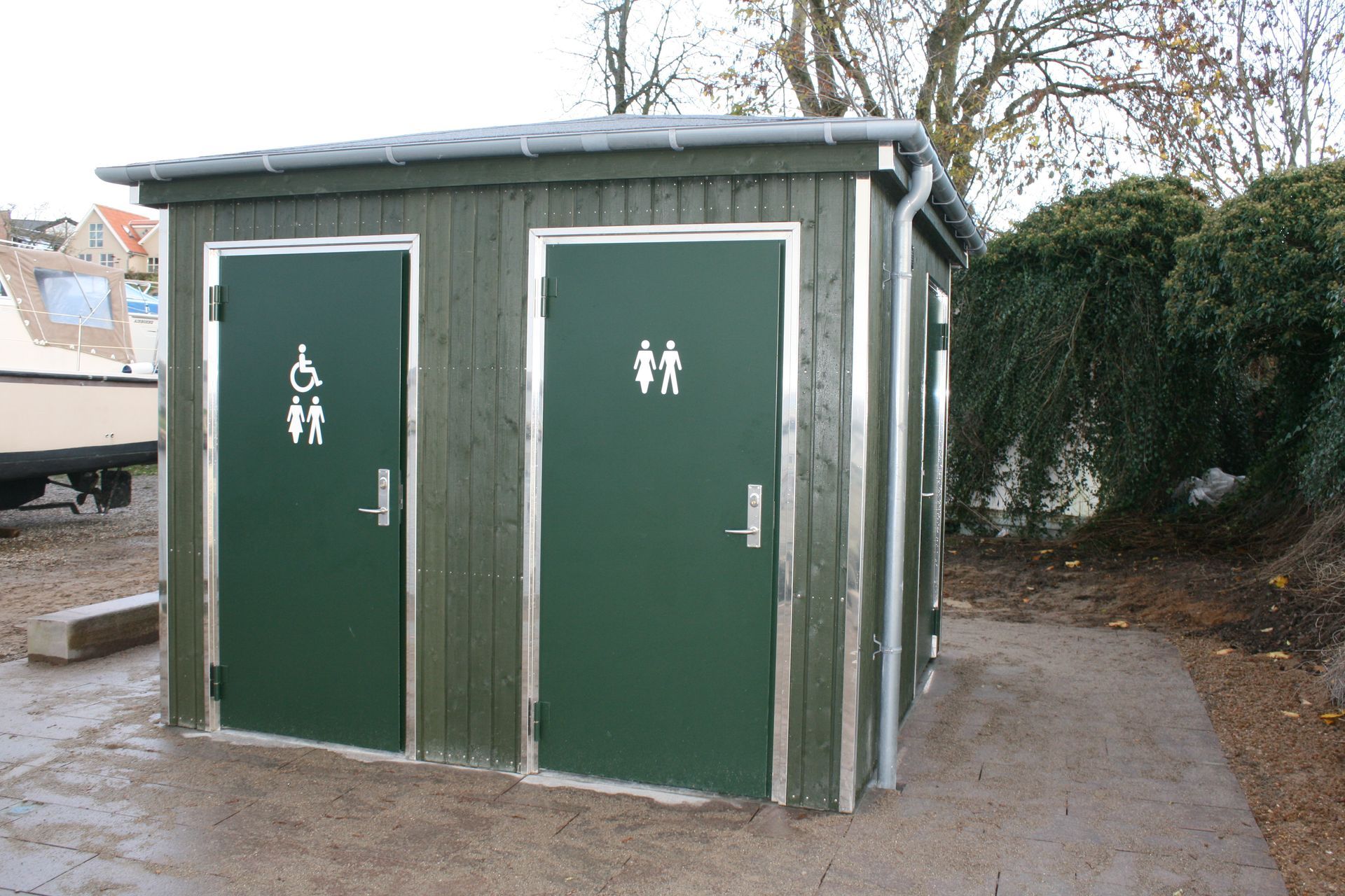 en lille træbygning med tre døre og et skilt foran