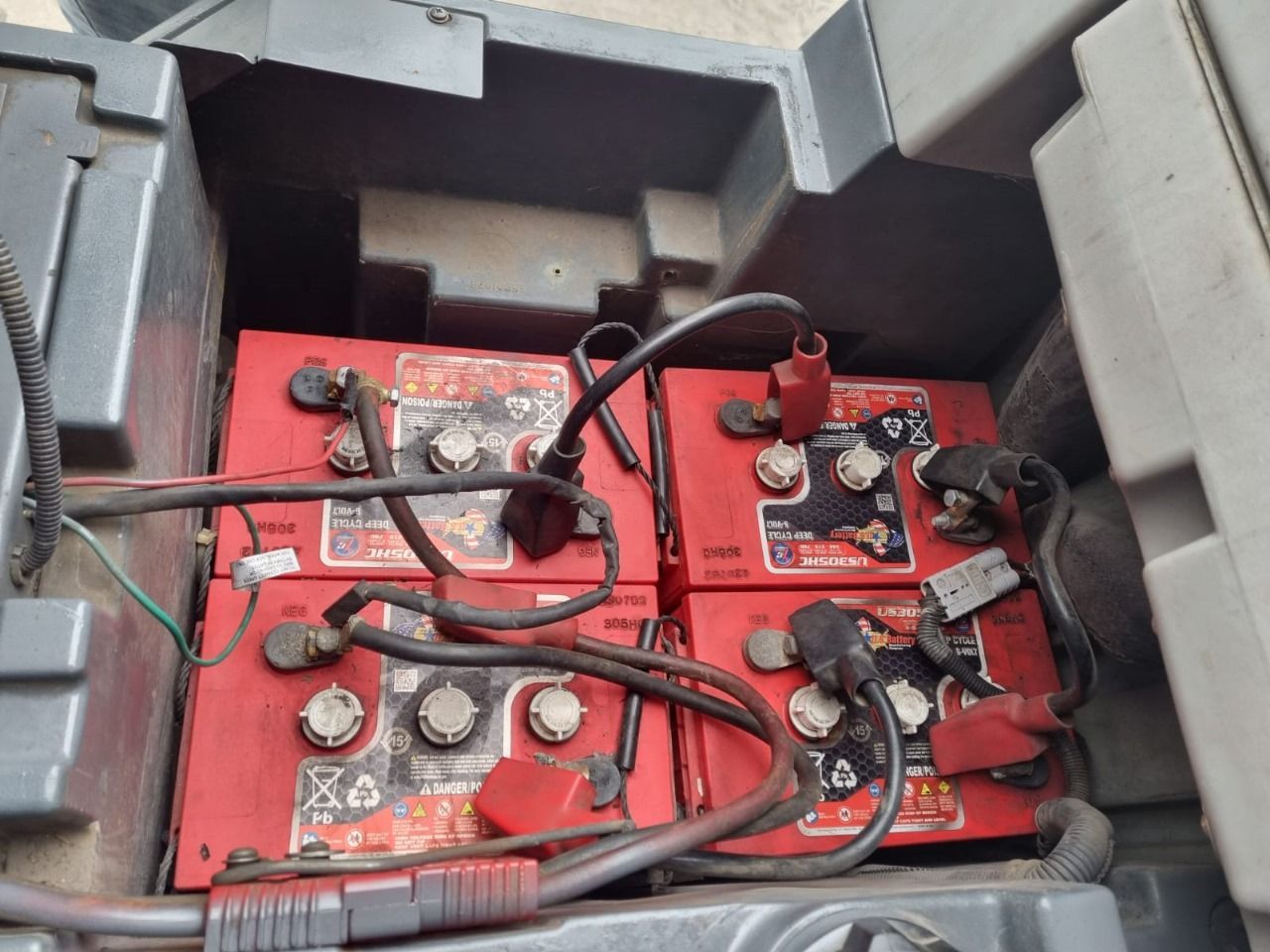 Cuatro baterías rojas conectadas en un compartimento, probablemente para un vehículo eléctrico.