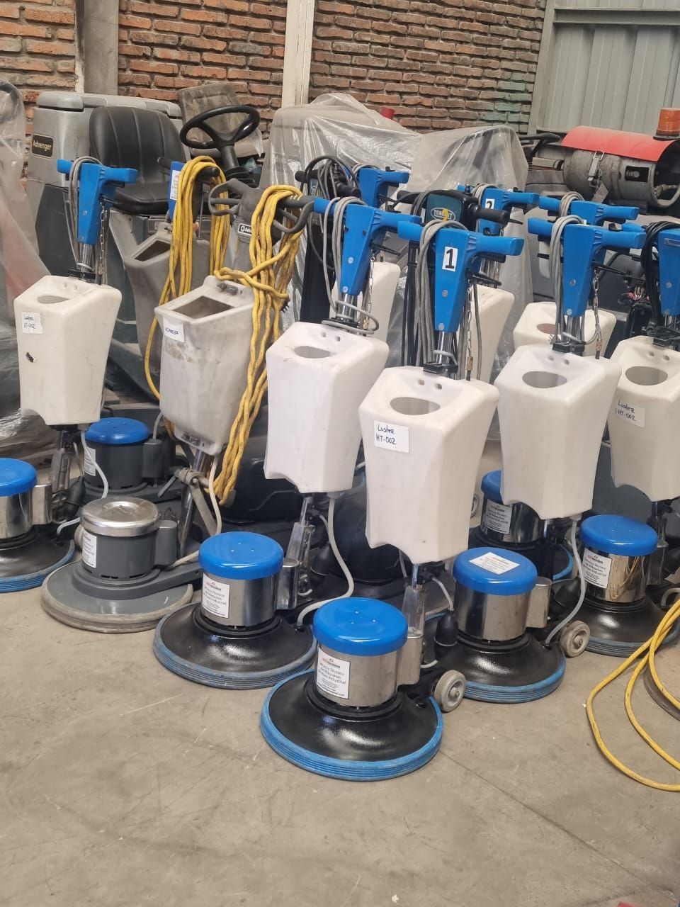 Pulidoras de pisos, blancas y azules, alineadas en un almacén.