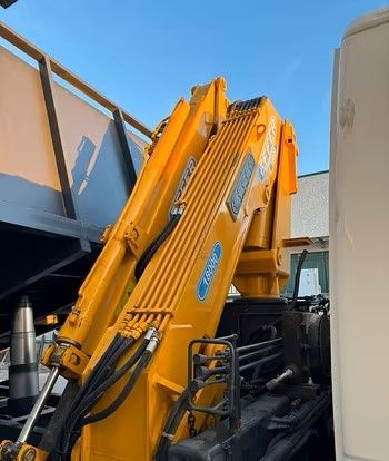 Una gru gialla è attaccata al retro di un camion.