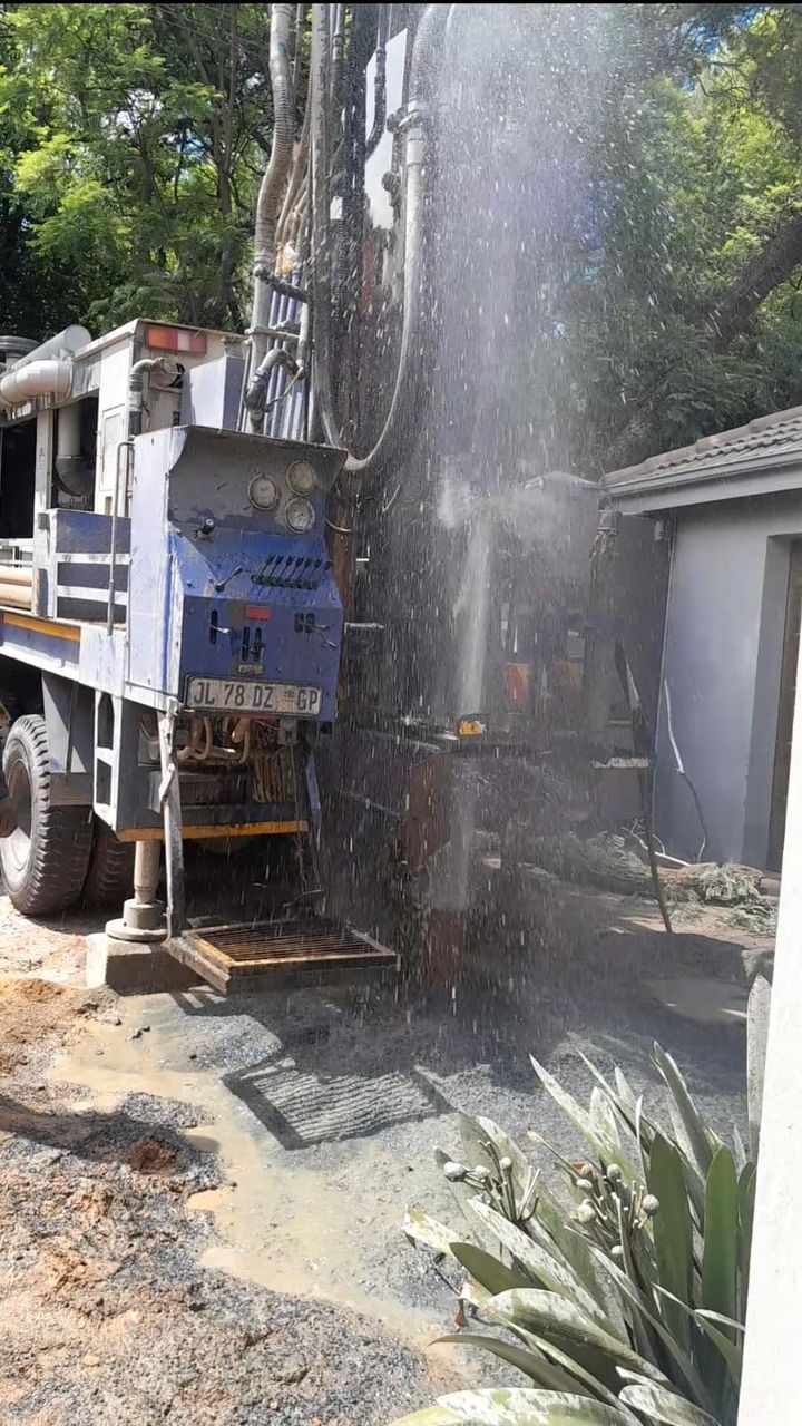 Borehole drilling machinery with water praying out of the ground