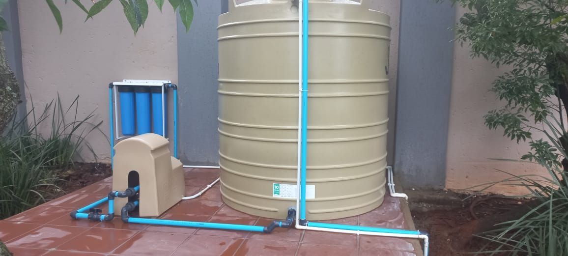 A man is working on a water filter on the side of a building.