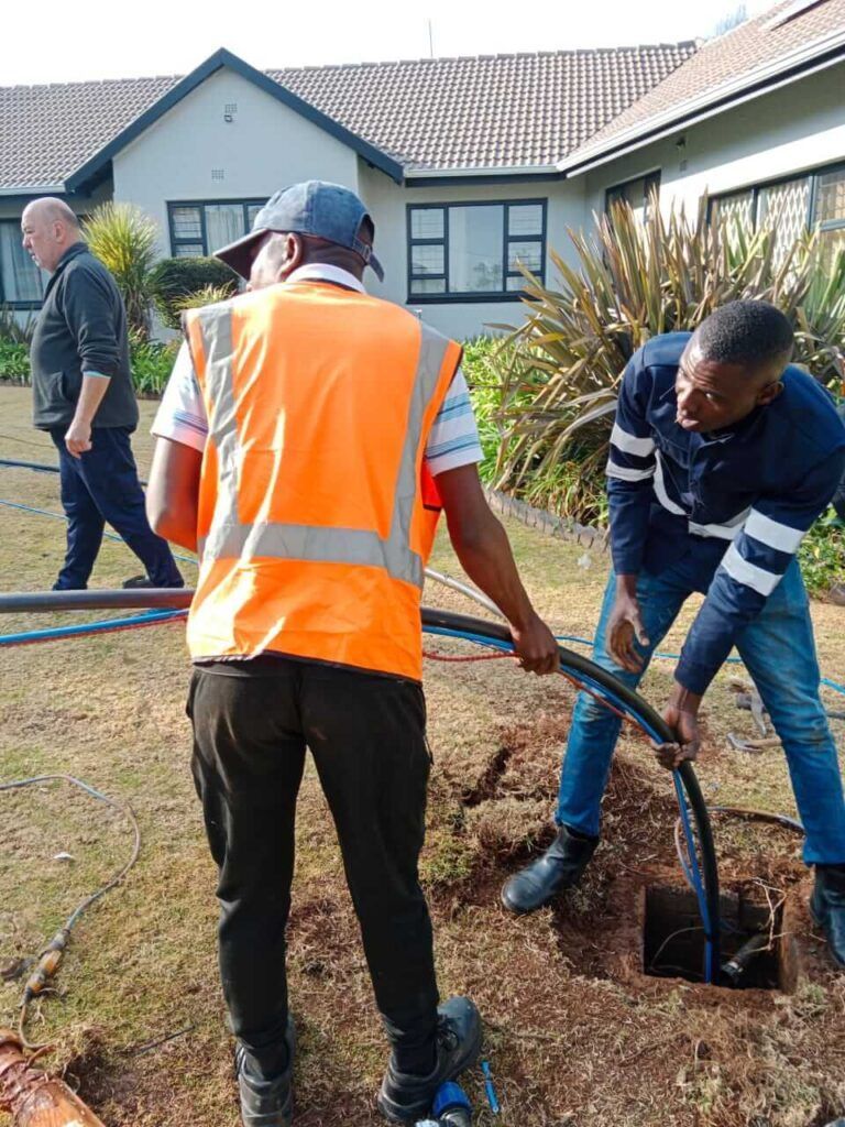 A group of men are working on a drain in a yard.
