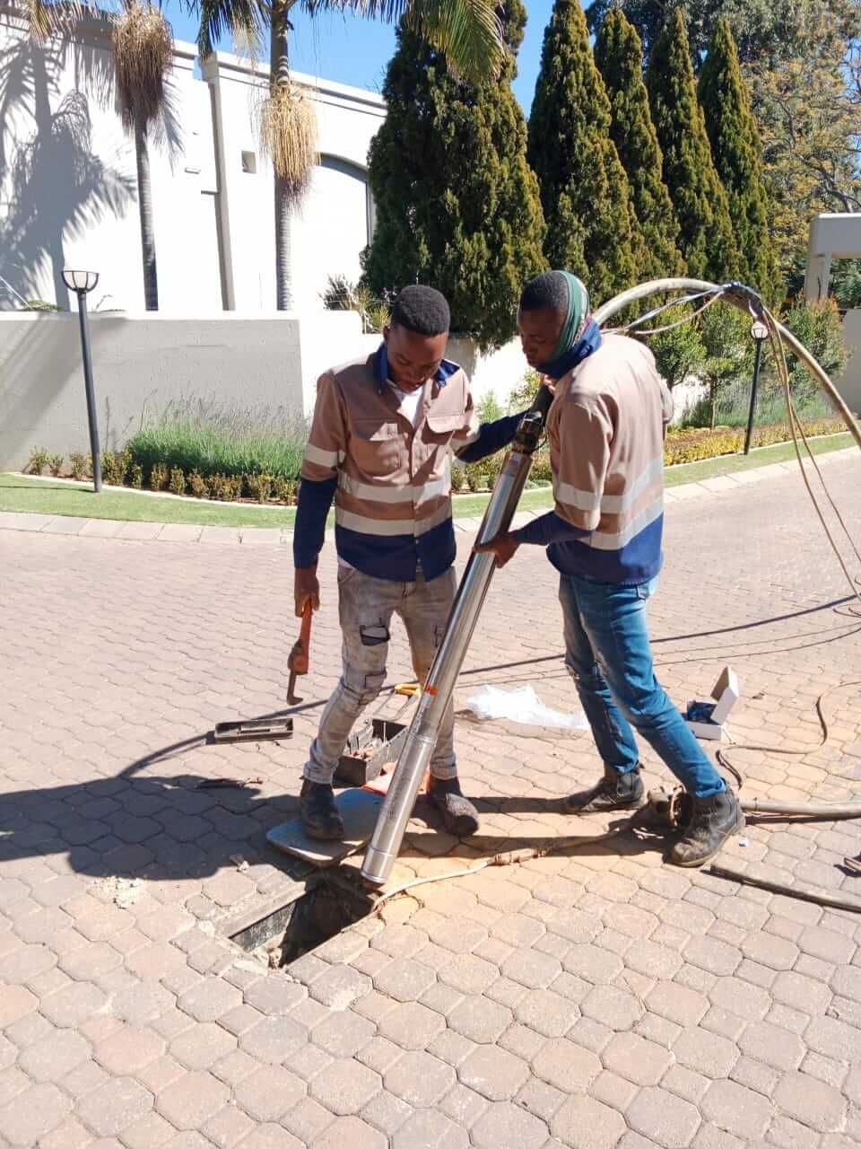 Two men are working on a hole in the ground