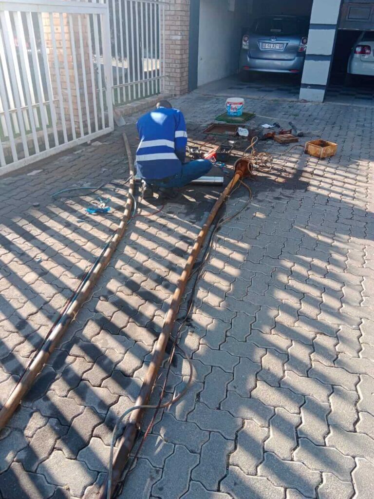 A man is working on a fence in a driveway.