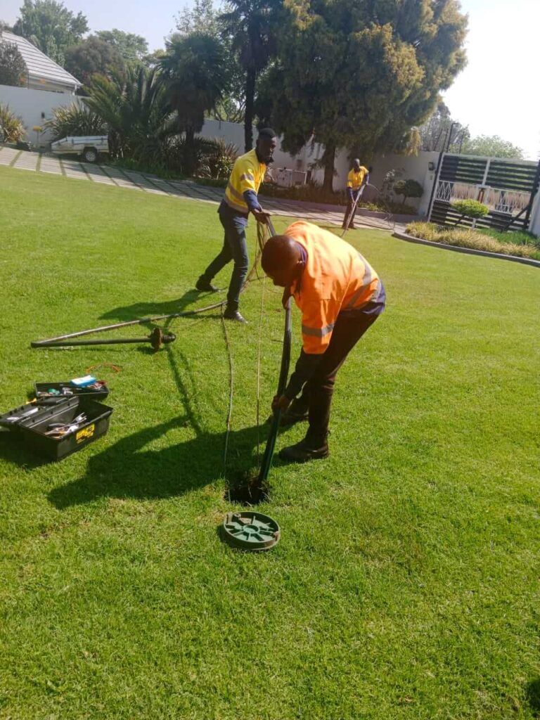 A man is digging a hole in the grass with a shovel.