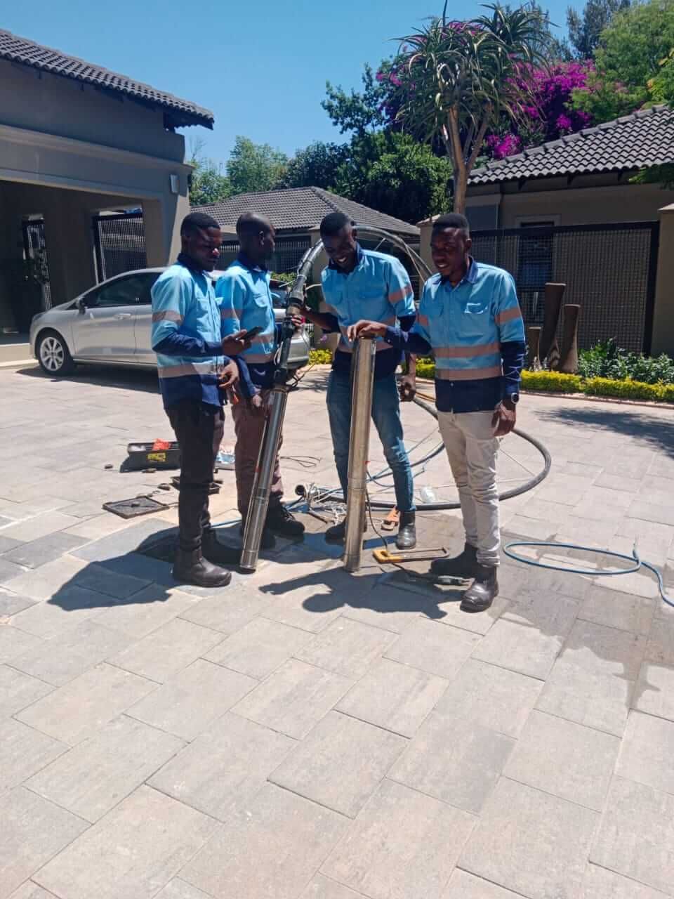 A group of men are standing on a sidewalk holding a snake.