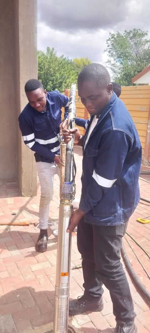 Two men are working on a water pump.