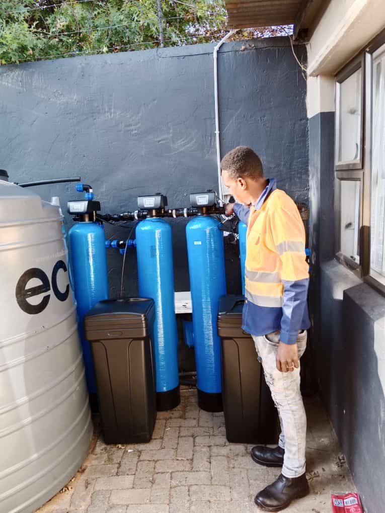 A man is standing in front of a water treatment system.