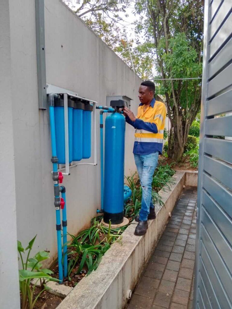 A man is working on a water filter on the side of a building.