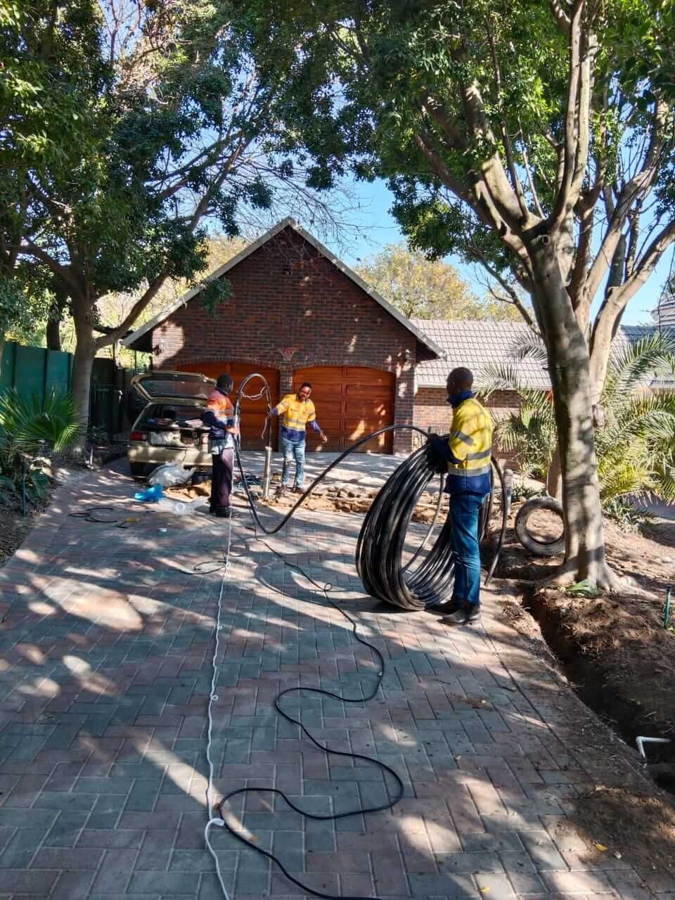 A group of people are working on a driveway in front of a house.