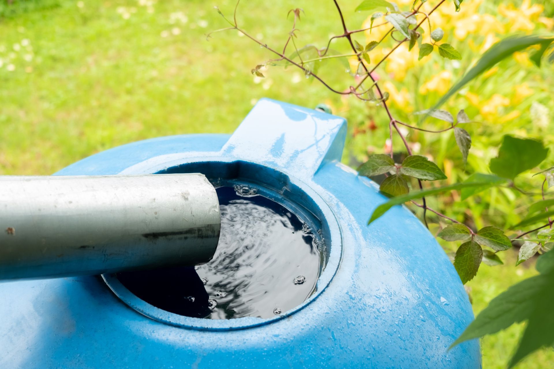 A blue water tank is being filled with water from a pipe.