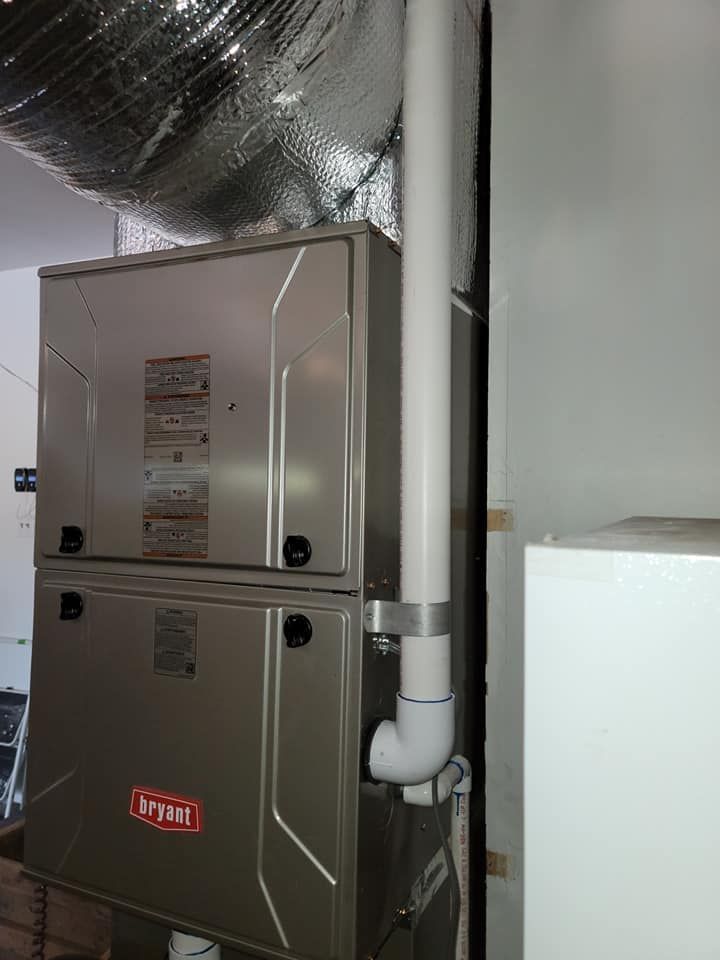 HVAC system in a basement; silver furnace with white PVC exhaust pipe.