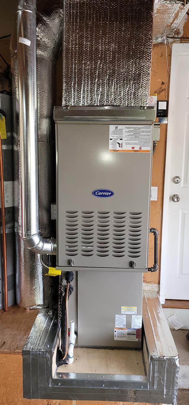 A Carrier furnace with a silver exterior, metal ductwork, and a shiny, insulated structure in a utility space.