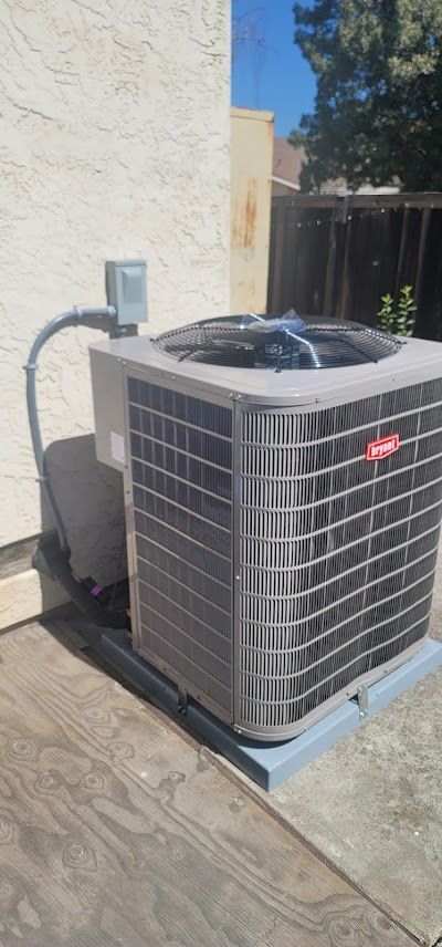 An air conditioning unit is outside next to a wall.