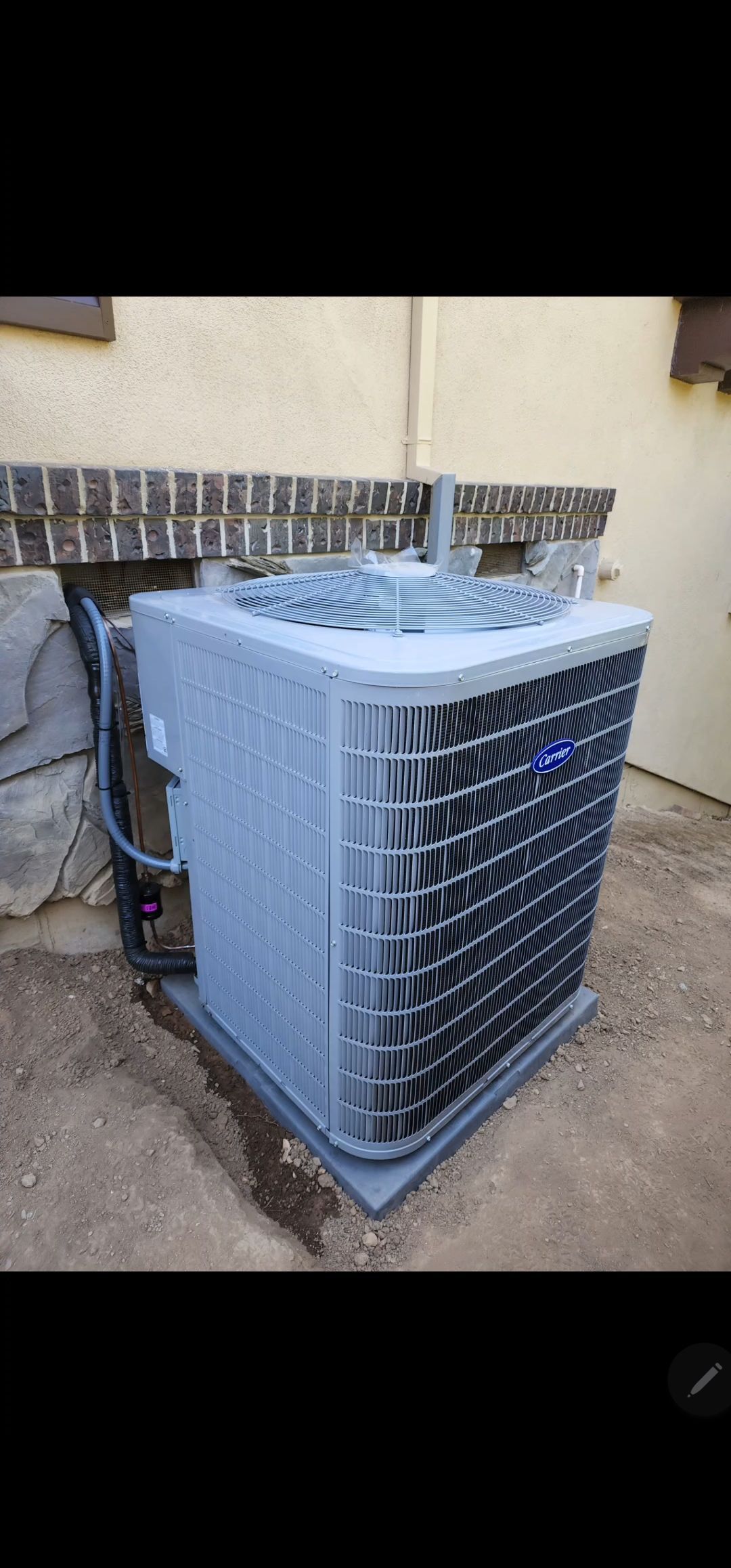 Air conditioning unit on a concrete pad next to a wall.