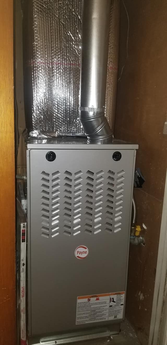 A furnace installed in a wooden cabinet, with a vent pipe attached to the top.