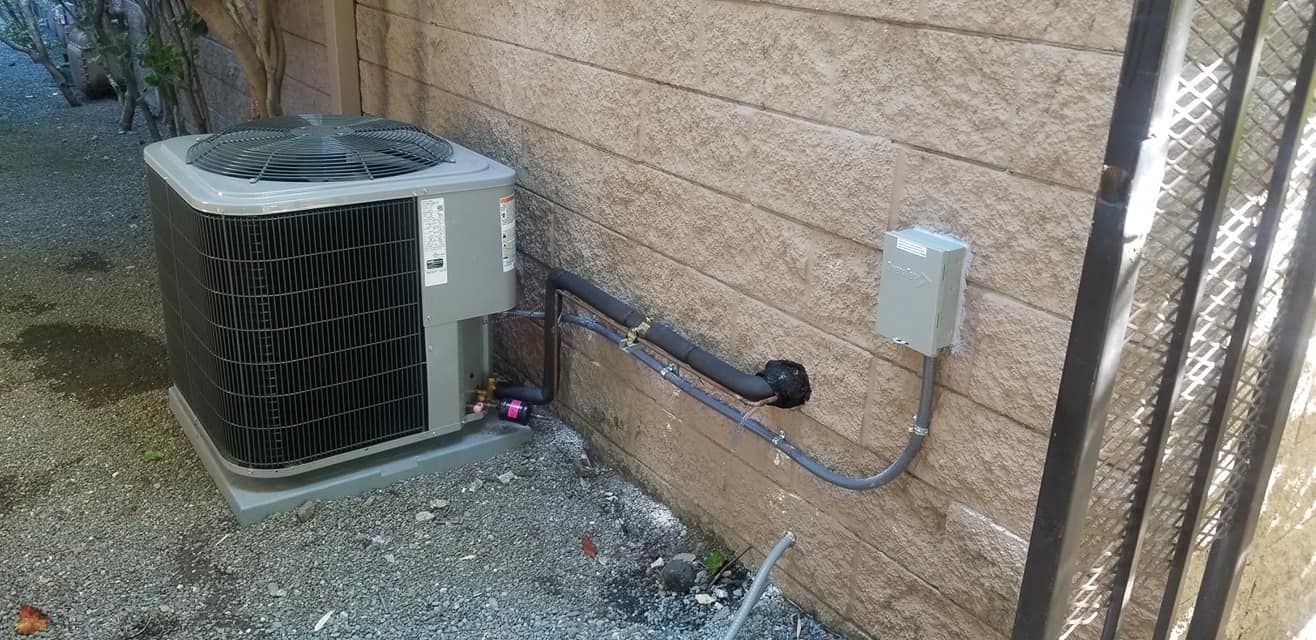Air conditioning unit next to a textured wall with an electrical box.