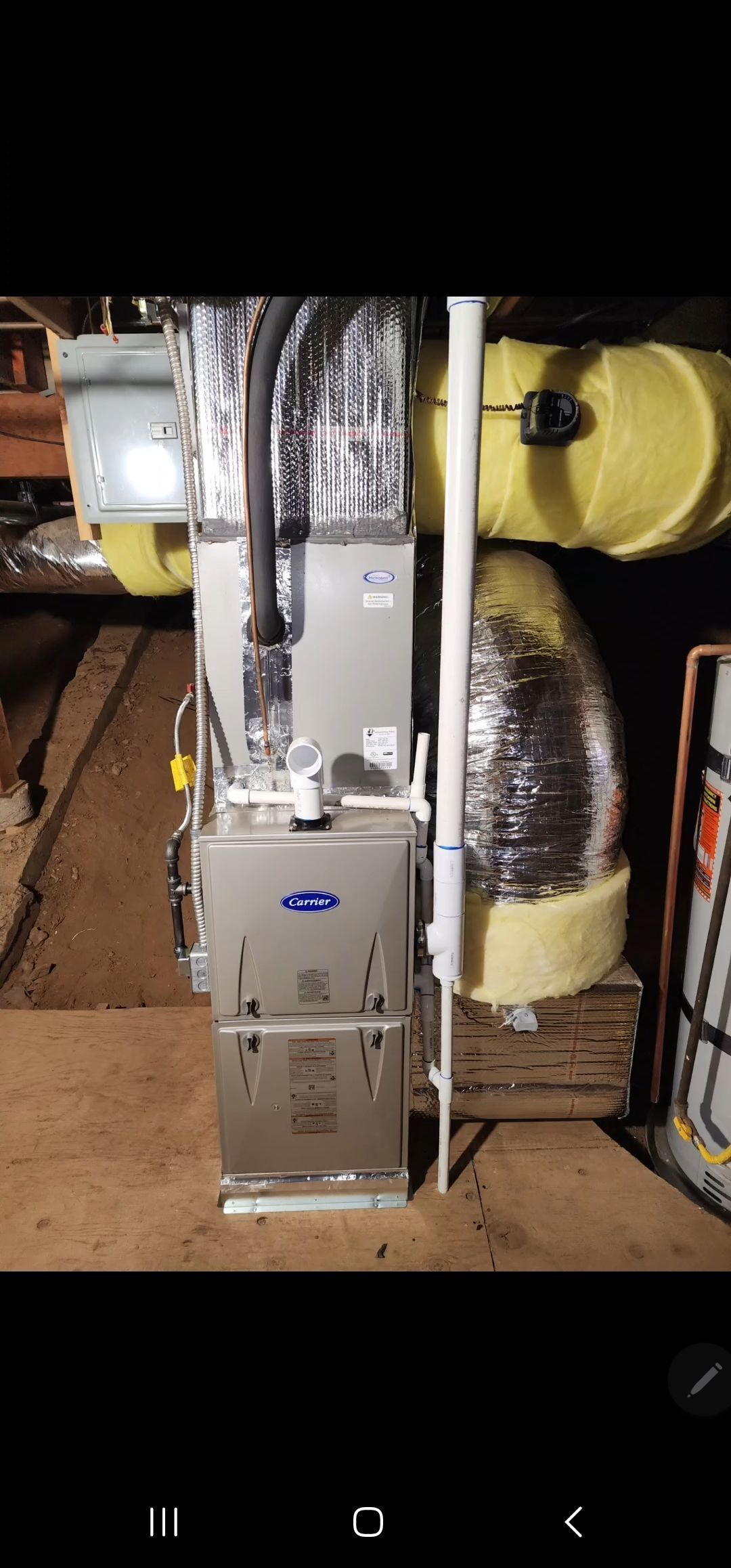 A person repairing a wall-mounted boiler with a screwdriver.