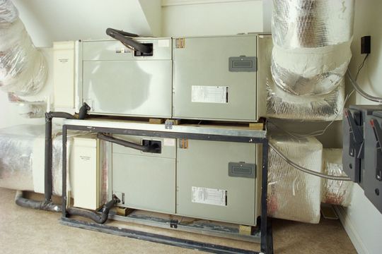 Two HVAC units stacked in an attic, with insulated ductwork.