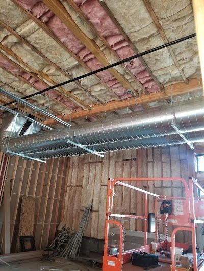 Interior of a building under construction, showing ductwork, insulation, and lift platform.