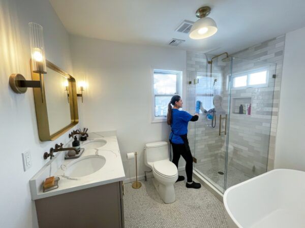 Cleaning shower glass with a blue cloth.