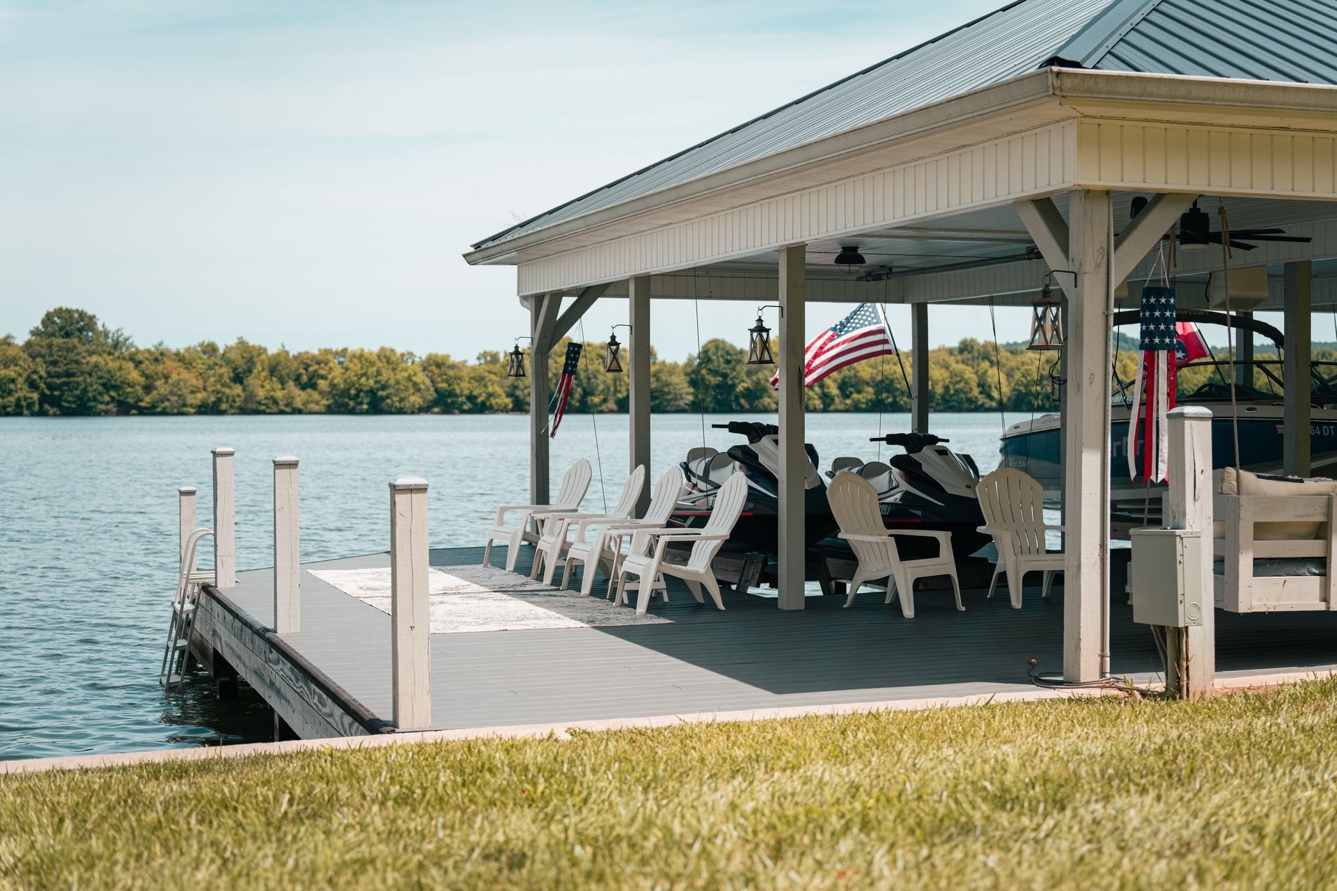 A dock with chairs and a pavilion overlooking a lake.