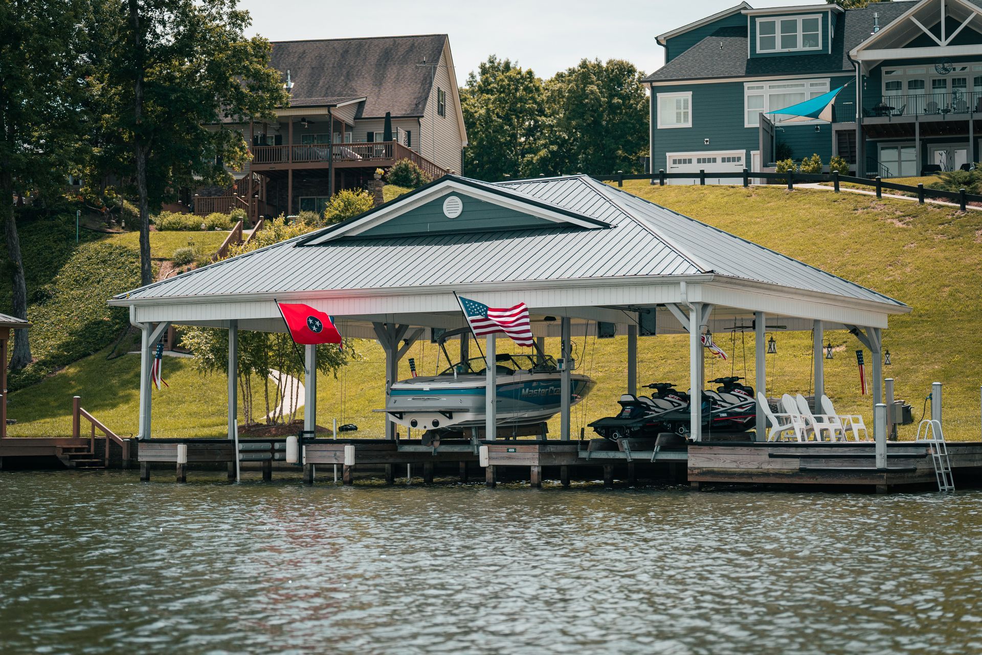 A boat is docked under a pavilion on the shore of a lake.