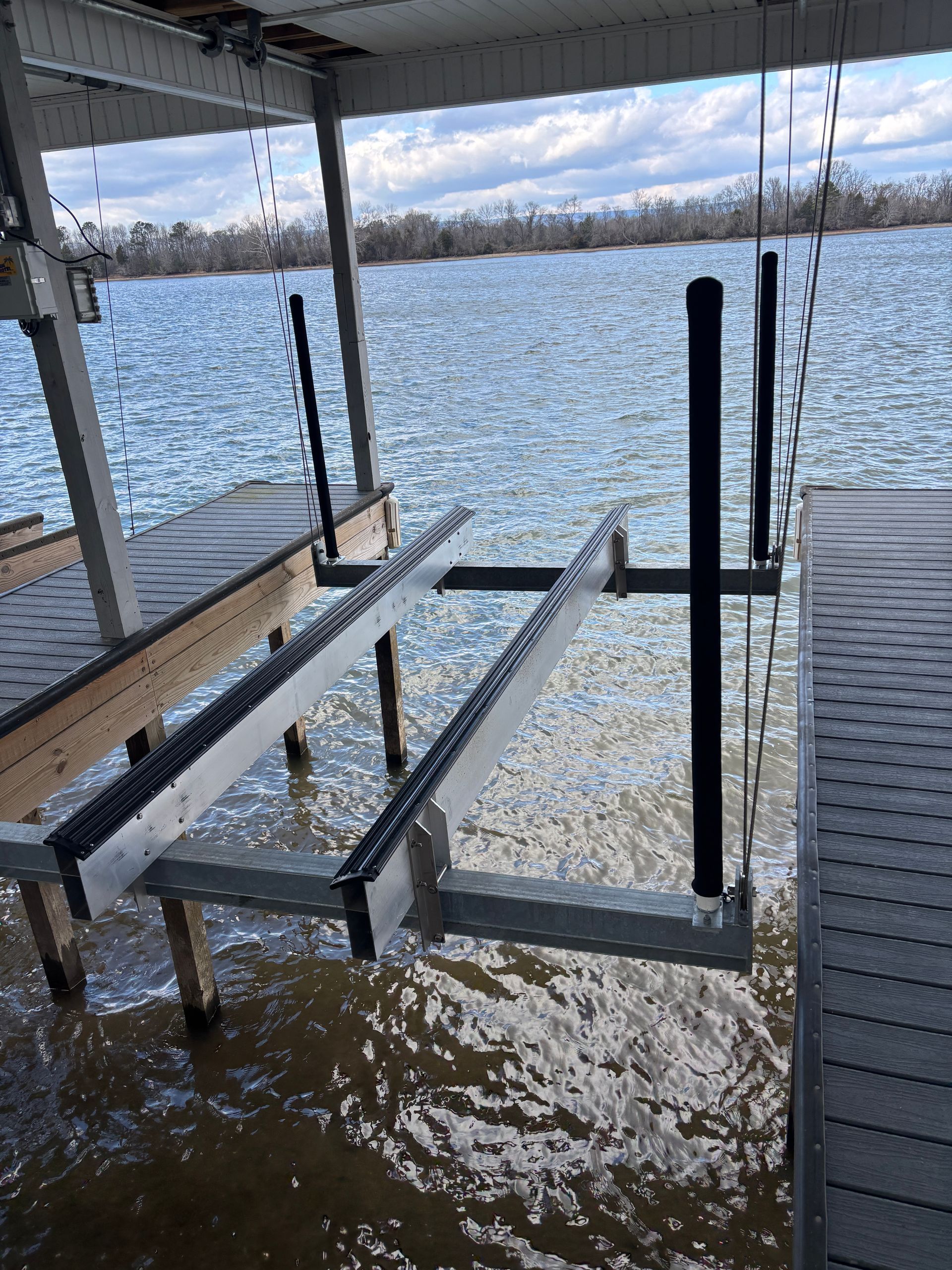 A boat lift is hanging over a dock in the water.