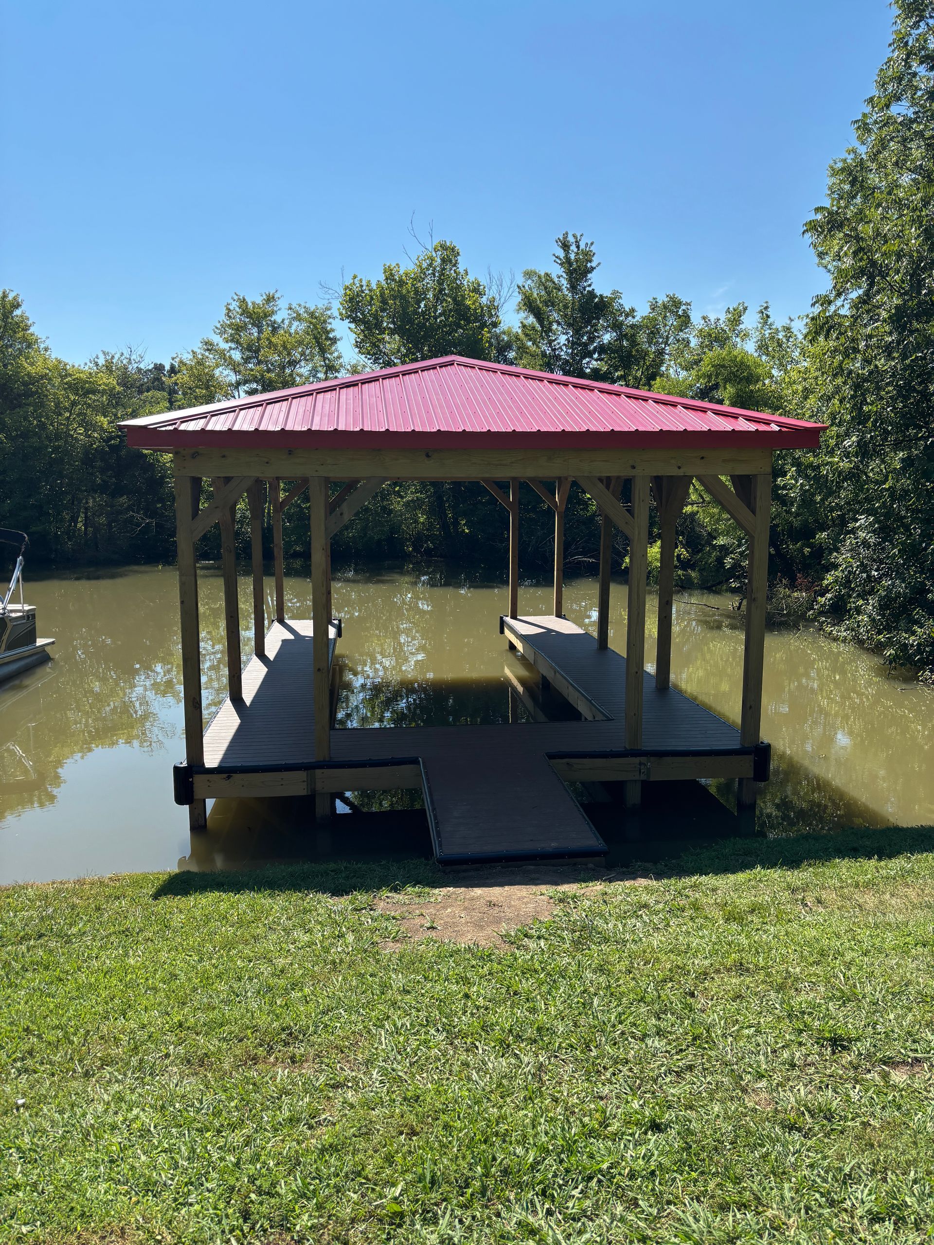 Dock with a red roof over two boat slips in a body of water.