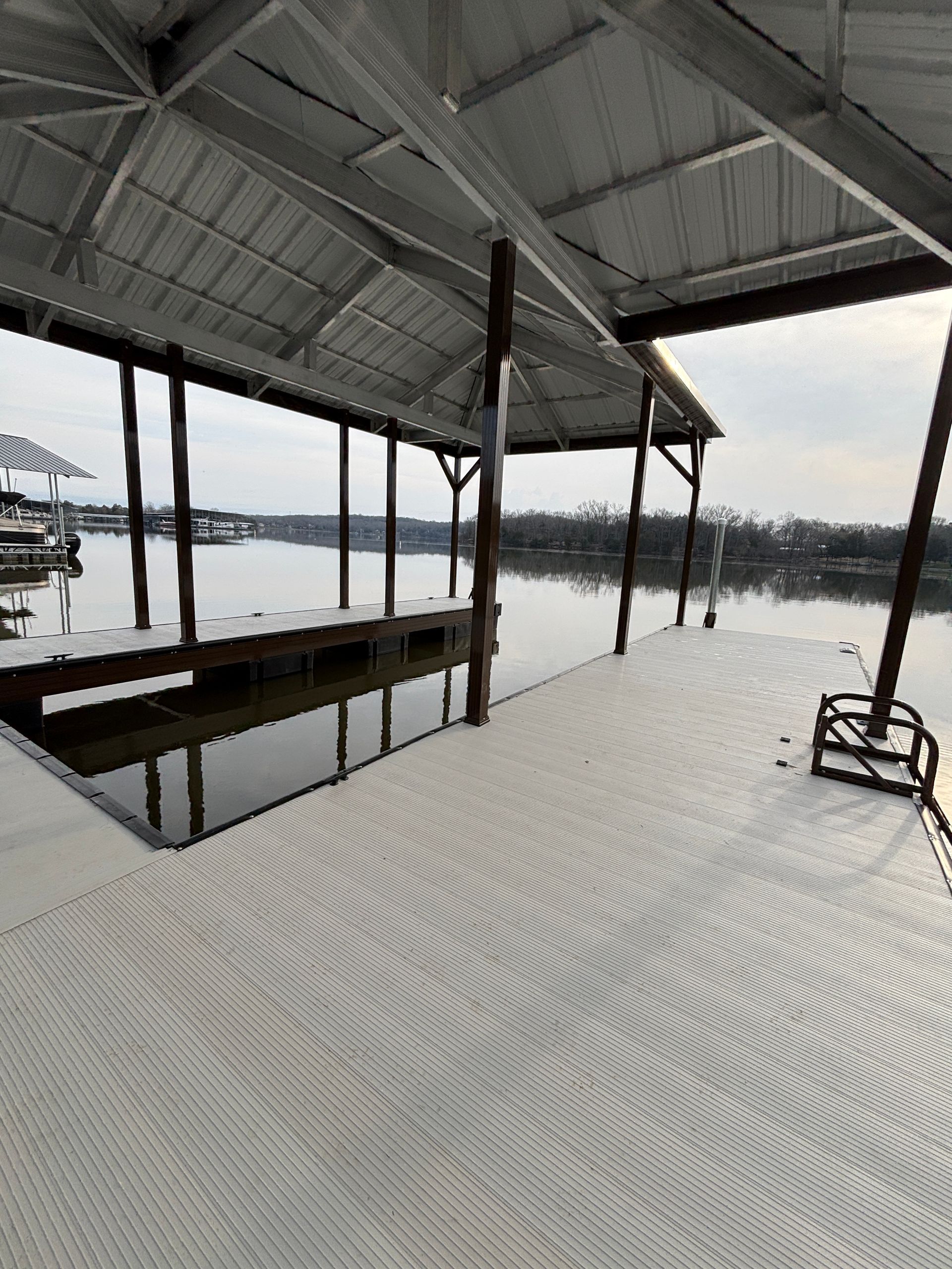 A dock with a roof overlooking a body of water.