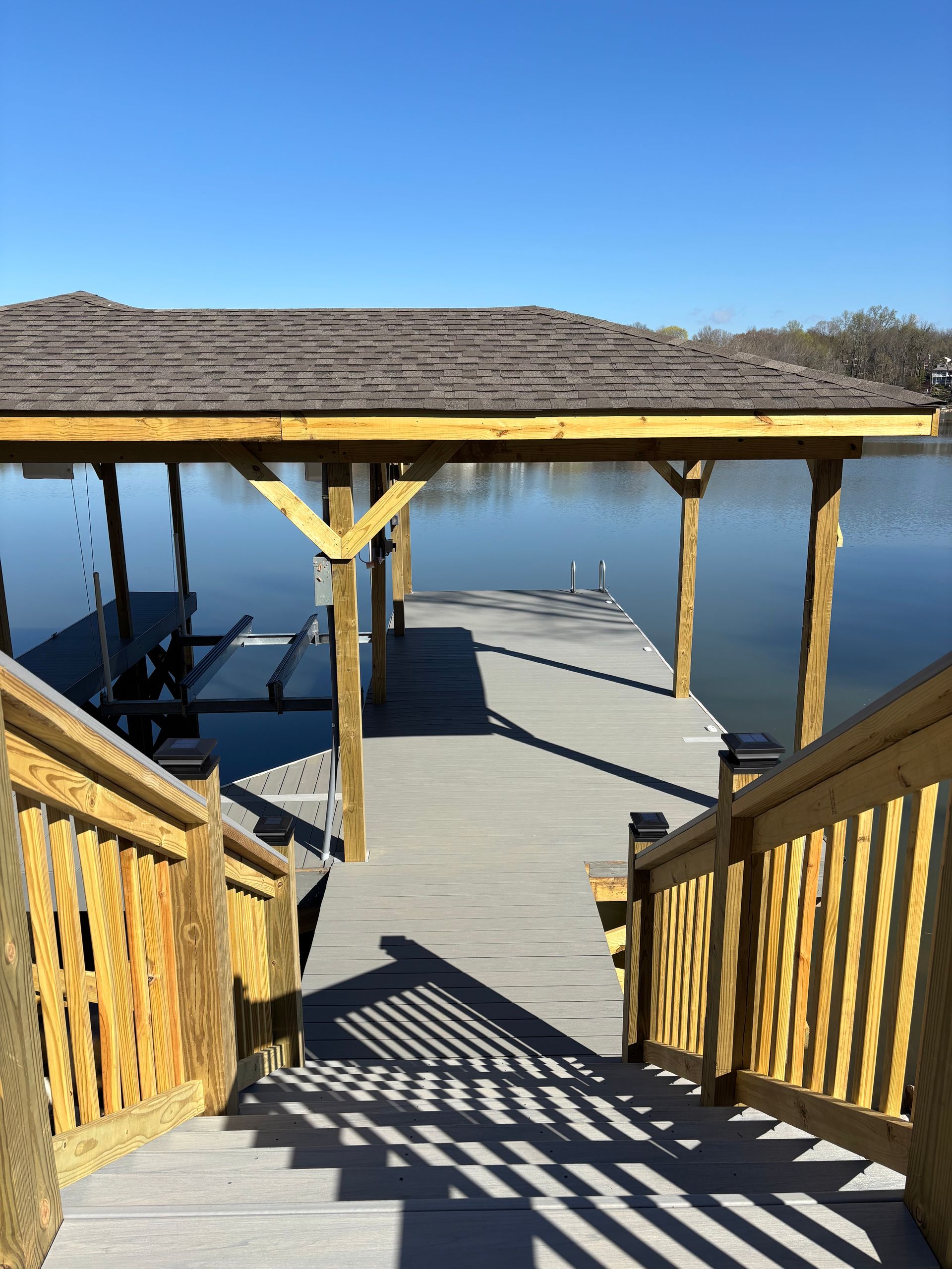 Wooden dock with stairs leading down to a lake. A roof covers the dock.