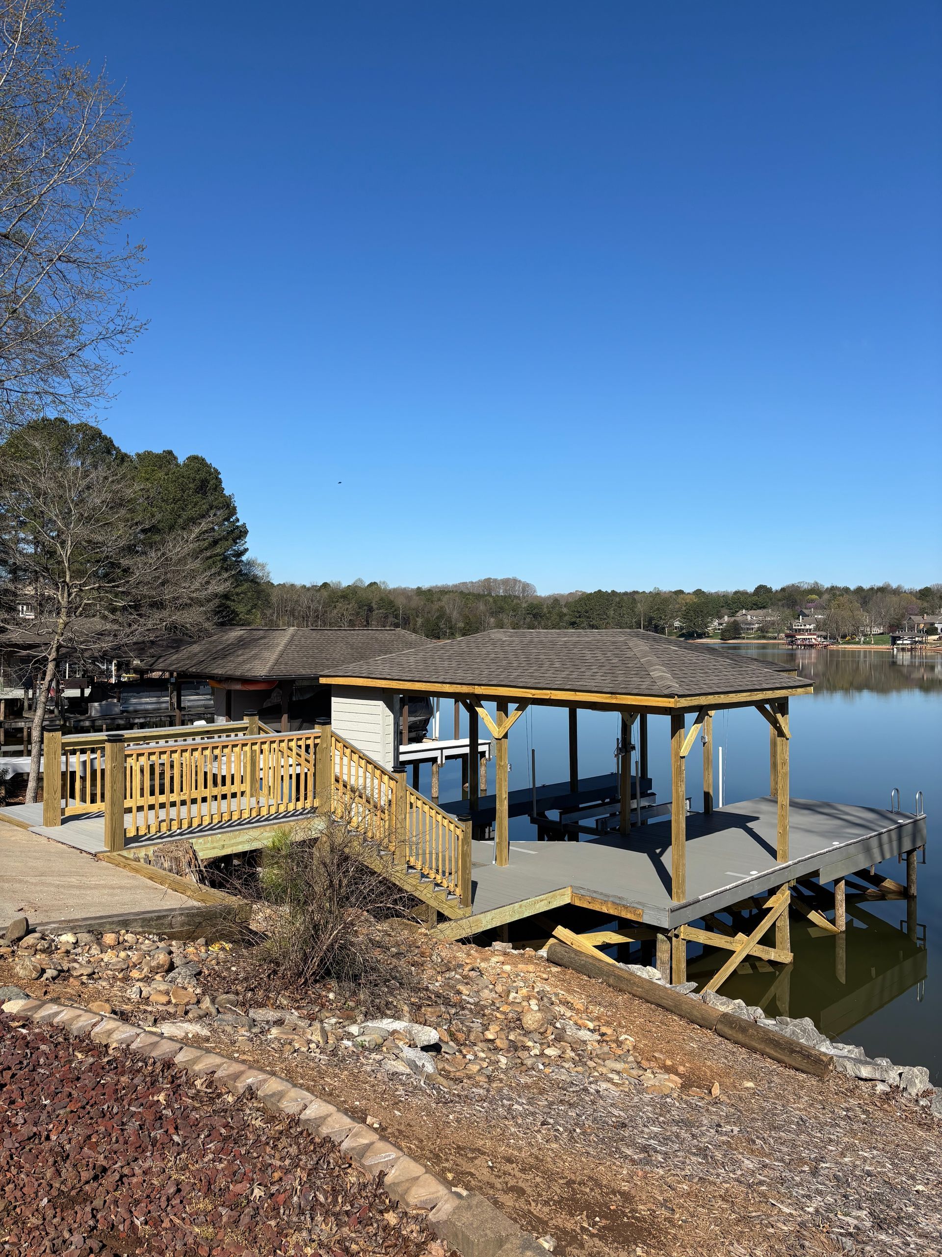 Dock with a gazebo-like covering on a lake; clear blue sky overhead.