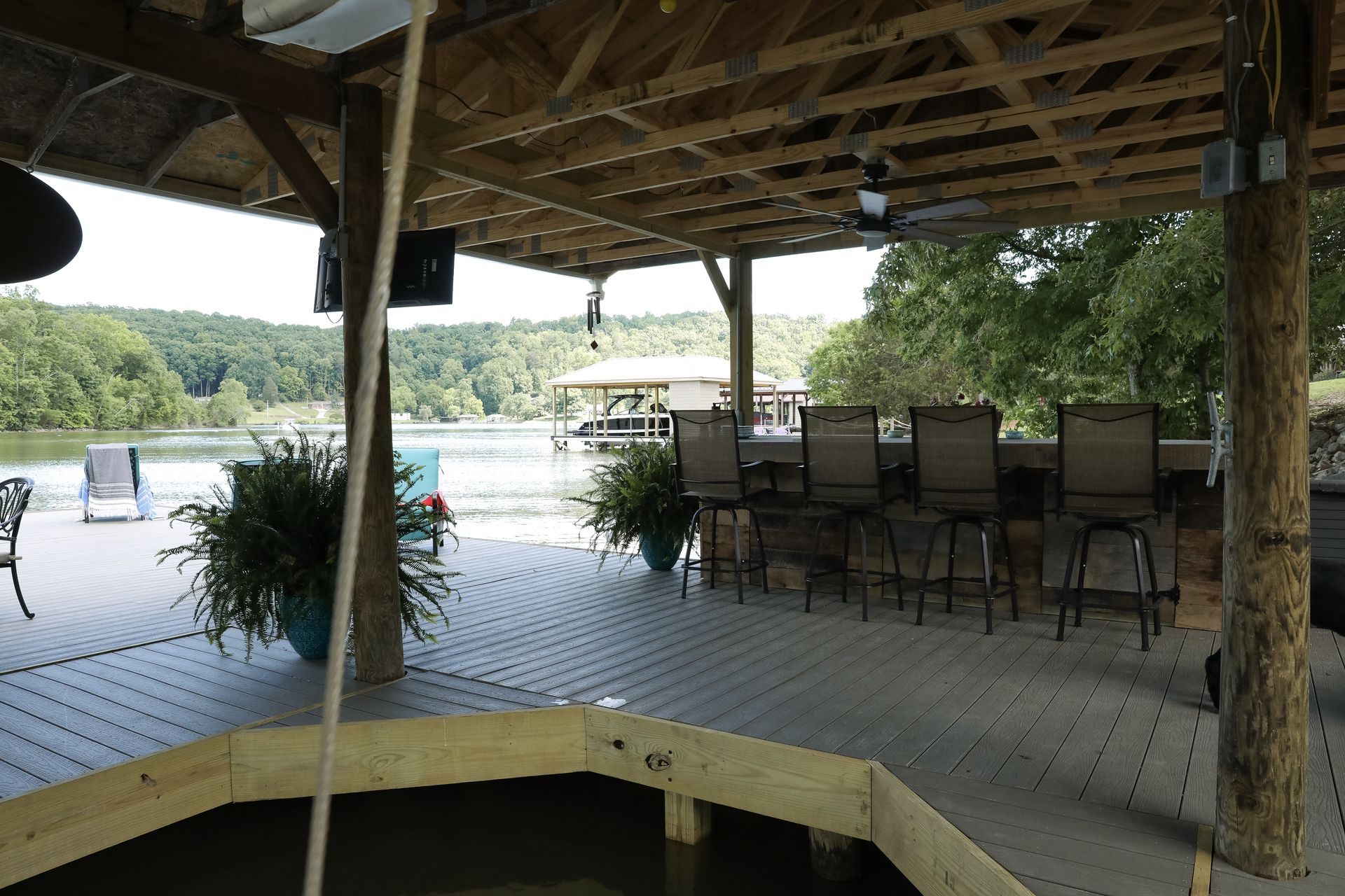 A covered deck with a table and chairs overlooking a lake