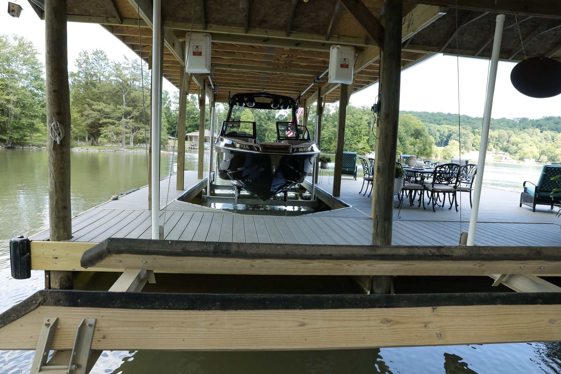 A boat is sitting under a covered dock on a lake