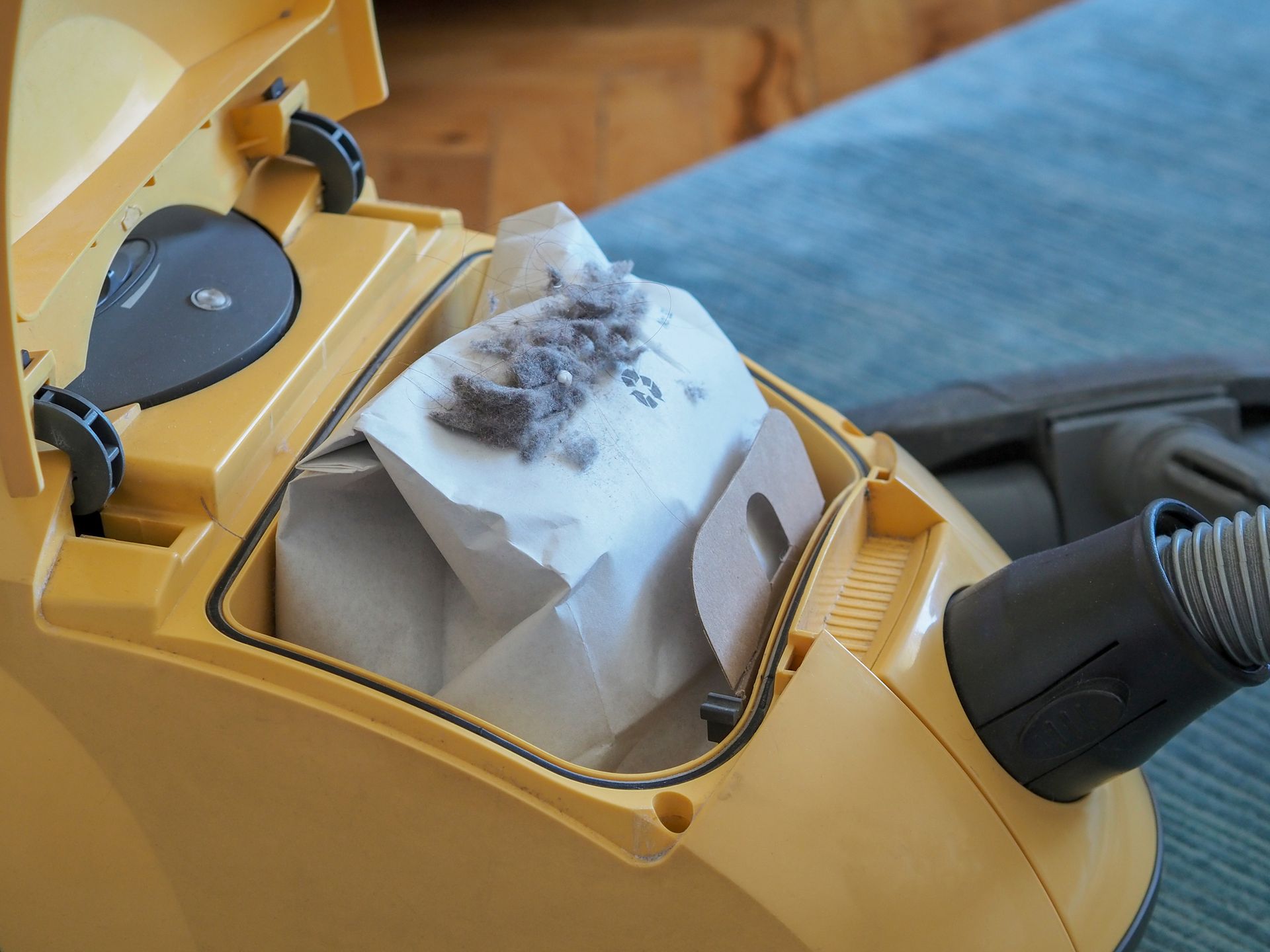 A yellow vacuum cleaner with a bag full of dust