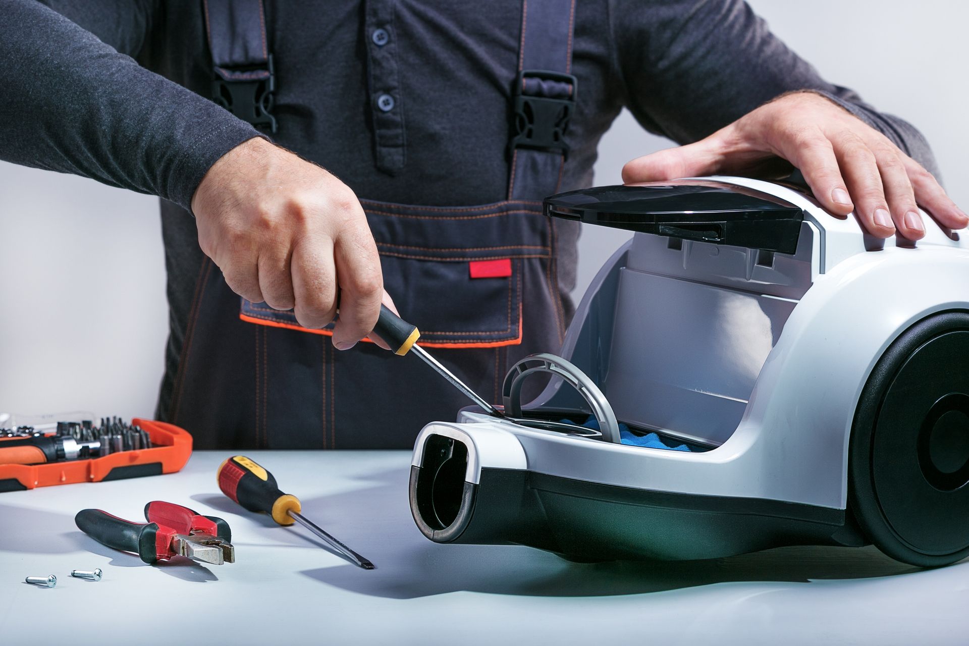 A person is fixing a robot vacuum cleaner on a table.
