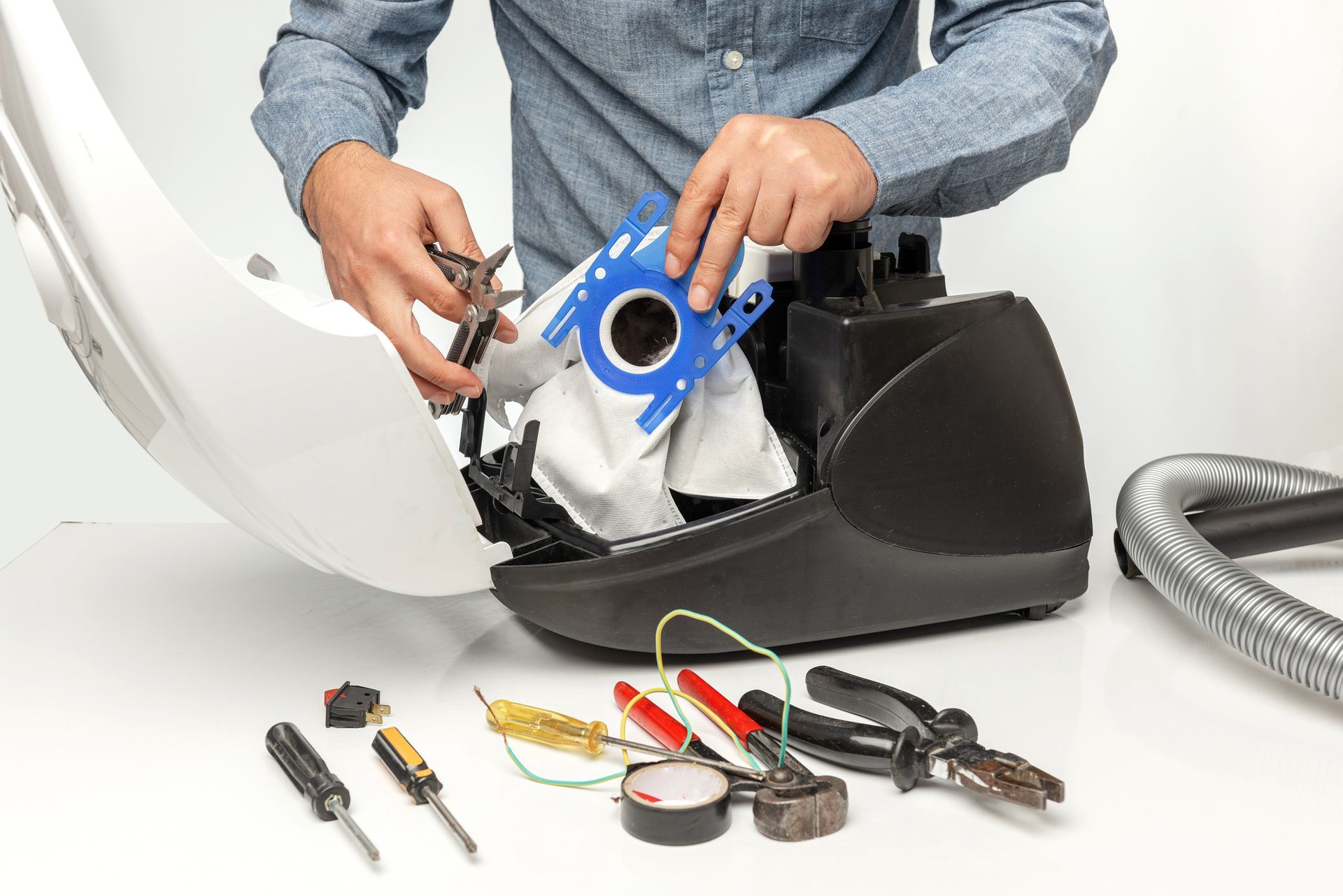 A man is repairing a vacuum cleaner with tools.