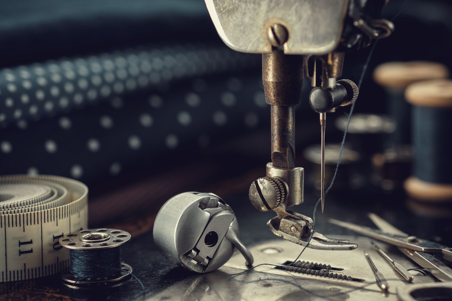 A sewing machine is sitting on a table next to a measuring tape and spools of thread.