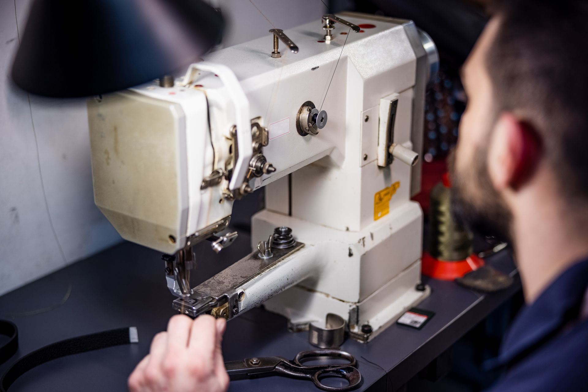 A man is working on a sewing machine in a workshop.