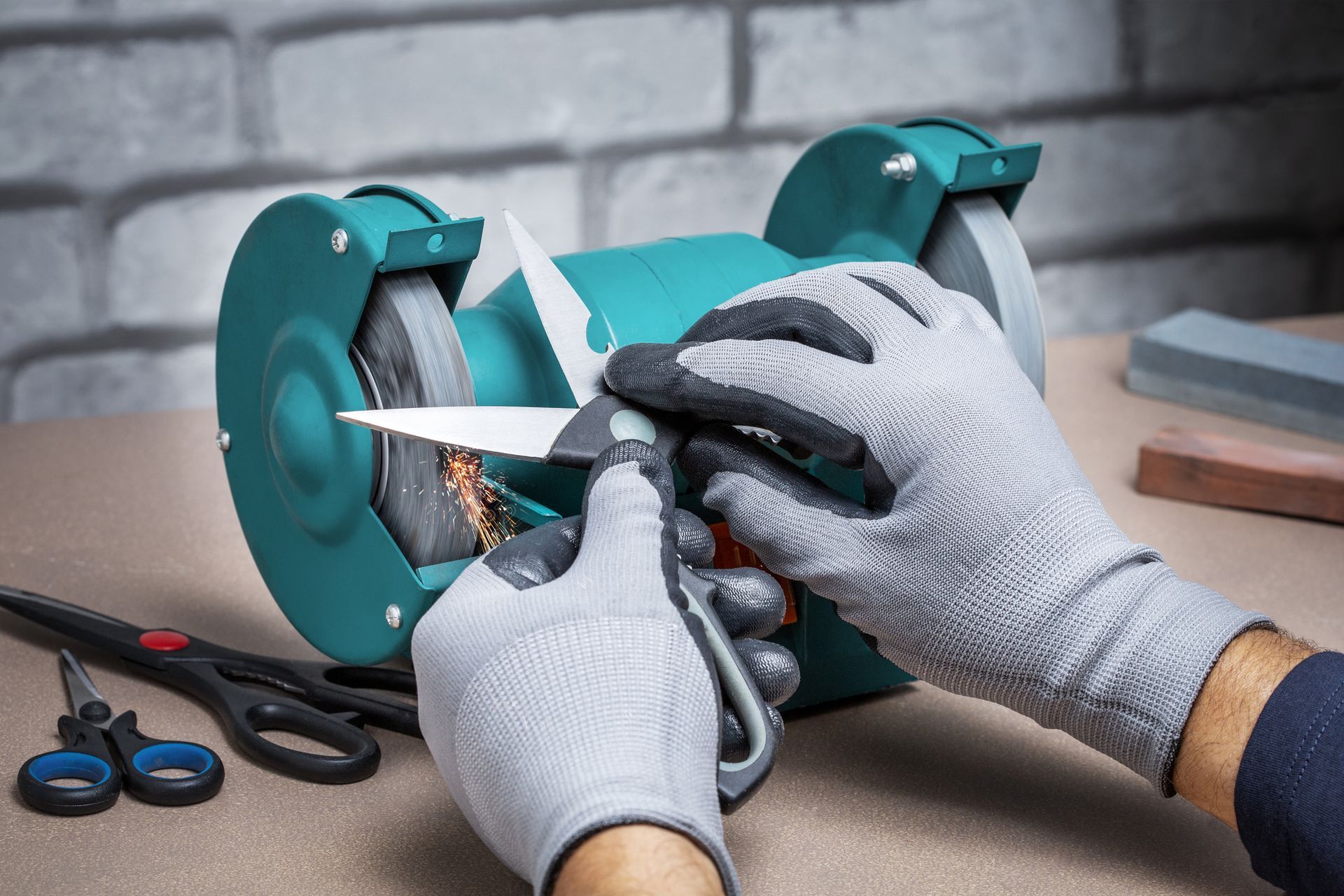 A person is sharpening a pair of scissors on a grinder.