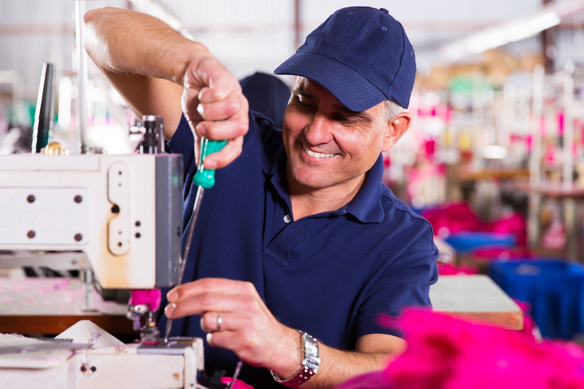 A man is working on a sewing machine in a factory.