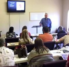 A man is giving a presentation to a group of people in a classroom.