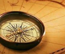 A compass is sitting on top of an old map.