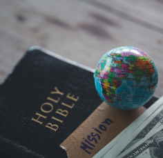 A globe is sitting on top of a holy bible.