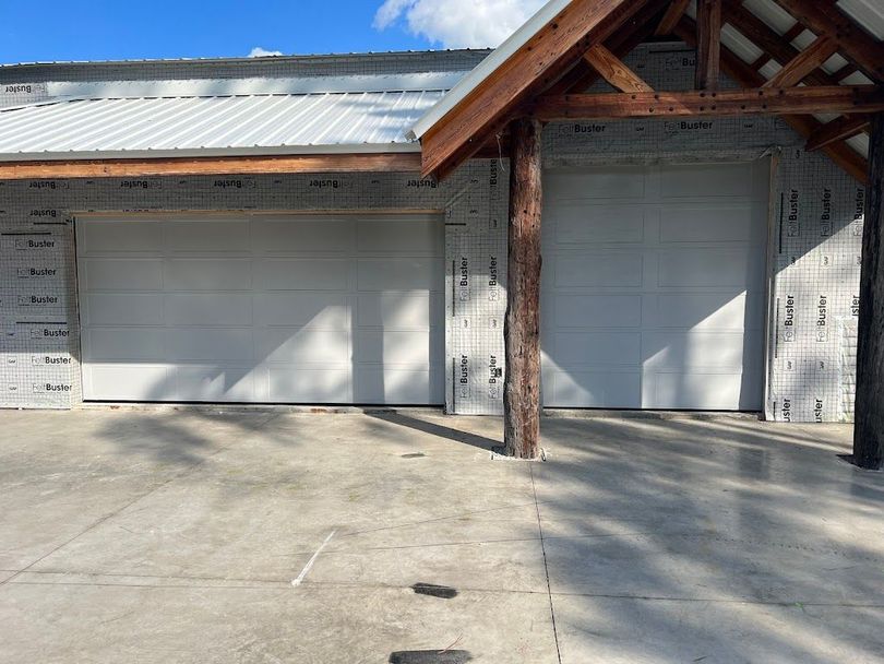 A garage with two white garage doors and a wooden roof.